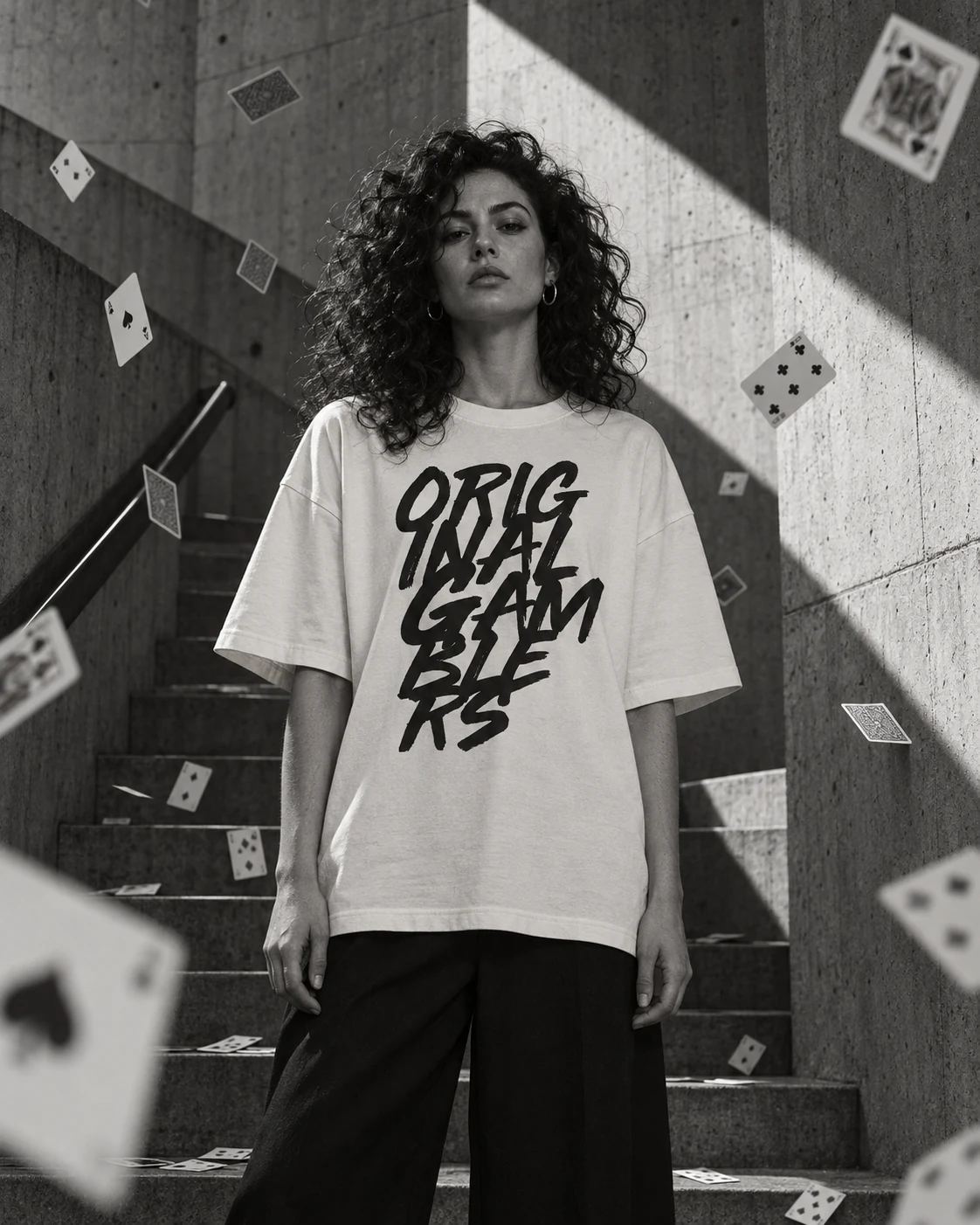 Persona con la Original Gamblers Tee crema en unas escaleras de concreto mientras caen cartas
